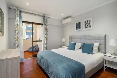 a bedroom with a large bed with blue pillows at Amendoeiras Family Apartment in Quarteira