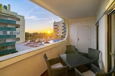 a balcony with a table and chairs and a window at Amendoeiras Family Apartment in Quarteira