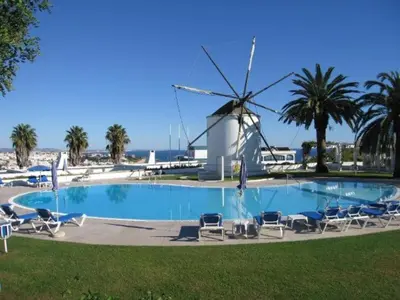 a pool with chairs and a windmill in the background at douceur d'algarve in Albufeira