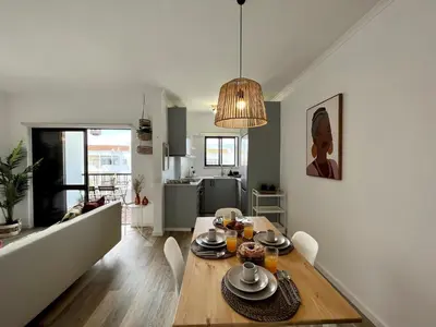 a dining room and living room with a wooden table at Albufeira Design by Homing in Albufeira