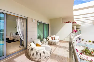 a living room with two wicker chairs and a balcony at Villa Seashell in Albufeira