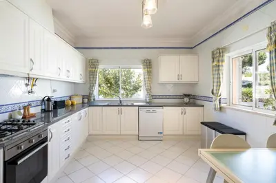 a kitchen with white cabinets and a stove top oven at Villa White Cottage by SAPvillas in Vilamoura