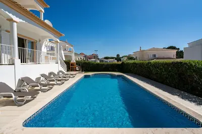 a swimming pool with chairs and a house at Villa White Cottage by SAPvillas in Vilamoura