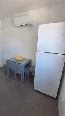 a kitchen with a table and a white refrigerator at Casa Rafinha in Faro
