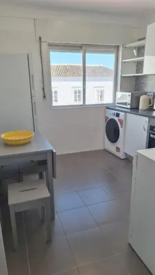 a kitchen with a table and a washing machine at Casa Rafinha in Faro