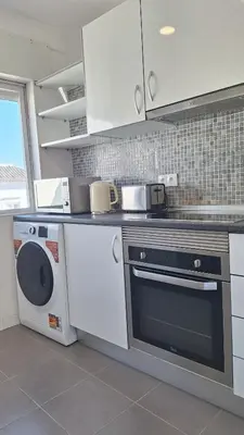 a kitchen with a stove and a washing machine at Casa Rafinha in Faro