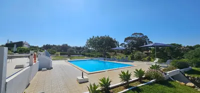 a swimming pool in a yard with an umbrella at Quinta do Lagar - 10 in Albufeira
