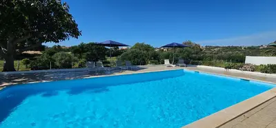 a blue swimming pool with chairs and umbrellas at Quinta do Lagar - 10 in Albufeira