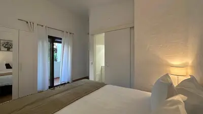 a white bedroom with a bed and a mirror at Golfinho by Check-in Portugal in Albufeira