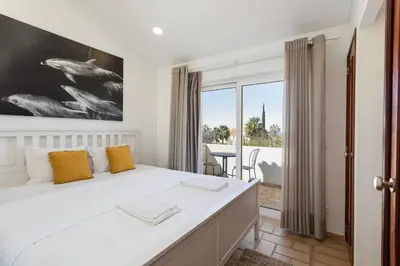 a bedroom with a large white bed with yellow pillows at The Albufeira Concierge - Villa Pool & Tennis in Albufeira