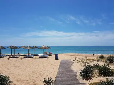 a beach with umbrellas and chairs and the ocean at The Albufeira Concierge - Villa Pool & Tennis in Albufeira