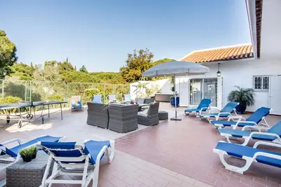 a patio with chairs and tables and an umbrella at Villa Patio in Albufeira