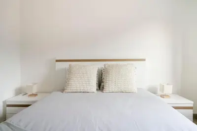 a bedroom with a white bed with two lamps at Casa Azinheira 1ºa- Albufeira in Albufeira