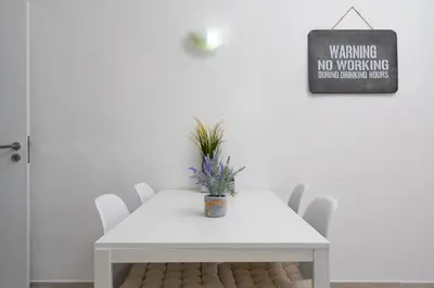a white dining room table with white chairs and a sign at Bright Albufeira - 5min to the beach by LovelyStay in Albufeira