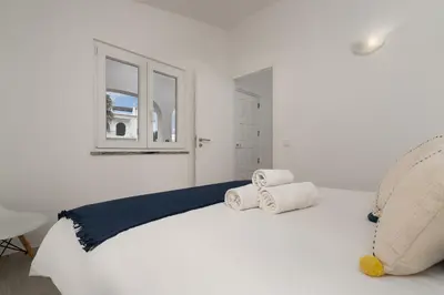 a white bedroom with a bed with towels on it at Bright Albufeira - 5min to the beach by LovelyStay in Albufeira