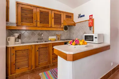 a kitchen with wooden cabinets and a bowl of fruit on a counter at Villa Jacaranda in Albufeira