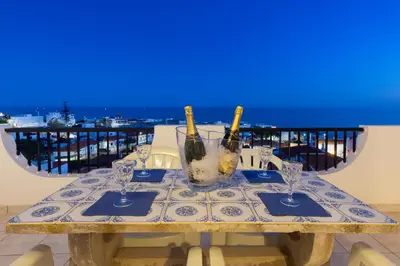 a table with wine bottles and glasses on a balcony at Oceanview Apartment A by Sequeira in Albufeira