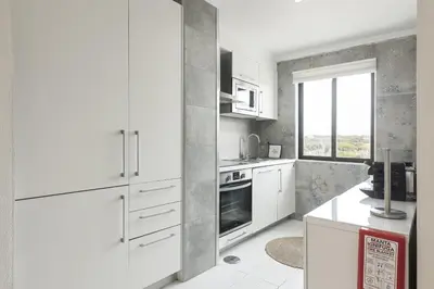 a white kitchen with white cabinets and a window at Scandic - City Center by HD Properties in Vilamoura