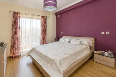 a bedroom with a large bed with a purple wall at Villa Anabela in Albufeira