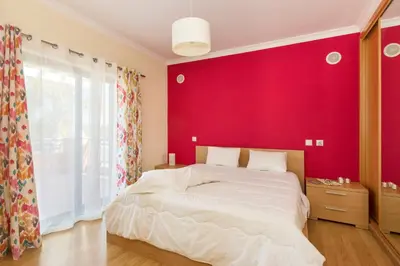 a bedroom with a large bed with a red wall at Villa Anabela in Albufeira