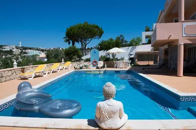a woman sitting in front of a swimming pool at Villa Malu in Albufeira