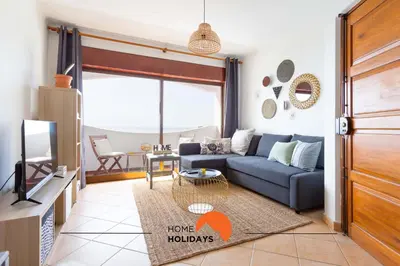 a living room with a blue couch and a tv at #114 T2 Foxy H by Home Holidays in Albufeira