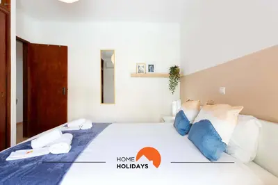 a bedroom with a white bed with blue pillows at #114 T2 Foxy H by Home Holidays in Albufeira