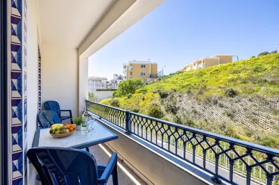a balcony with a table and chairs and a hill at Jacaranda in Albufeira