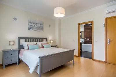 a bedroom with a large bed and a bathroom at Villa Casa Vilas Boas in Albufeira