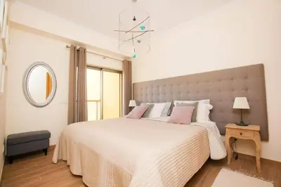 a white bedroom with a large bed with pink pillows at Jardins da Marina Albufeira in Albufeira