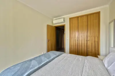 a bedroom with a bed and a wooden closet at Vista das Ondas - Apartamento 204 in Albufeira