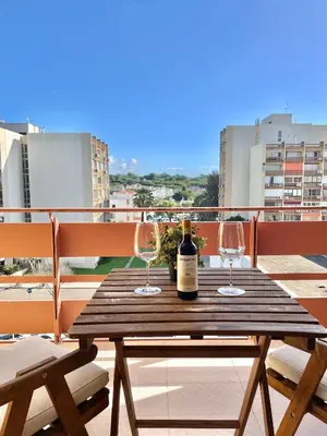 a wooden table with two wine glasses on a balcony at F&V Studio Vilamoura in Quarteira