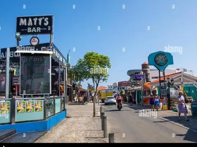a street in a town with people walking on the sidewalk at Perfect location for nightlife @ the Strip in Albufeira