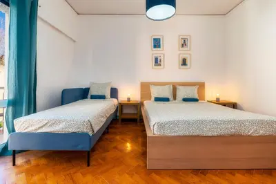 a bedroom with two beds and a blue chair at Happen!ng 2 in Faro