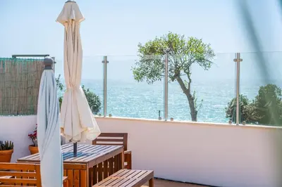 a balcony with an umbrella and chairs and a view of the ocean at Stunning terrace with ocean view in Albufeira