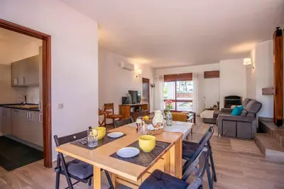a dining room and living room with a table and chairs at Casa da Aldeia in Albufeira