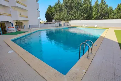 a large blue swimming pool in front of a building at Go4Portugal - Dinis - Luxe Condo with Pool, Airco, Seaview with two Balcony in Albufeira