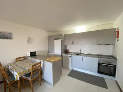 a kitchen with white cabinets and a table and chairs at House Т1 Bella Vista in Albufeira