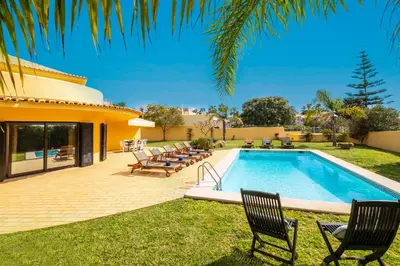 a swimming pool with chairs and a house at Villa Samui by Algarve Vacation in Albufeira