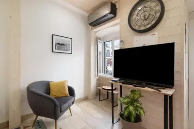a living room with a tv and a chair and a clock at Casa na Travessa 2 in Faro