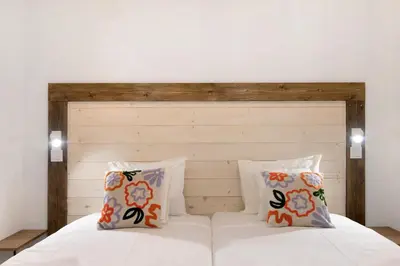 a bedroom with a white bed with a wooden headboard at Casa na Travessa 2 in Faro