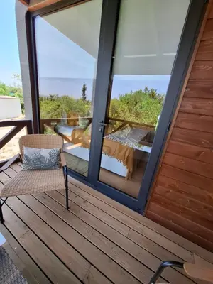 a room with a glass door and a chair on a deck at Eco Lodge Villa das Alfarrobas com Piscina in Algoz
