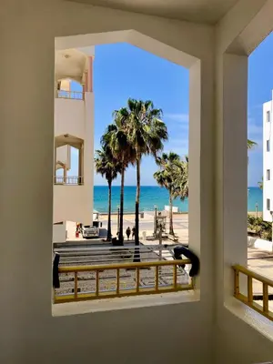 a view from a window of the beach and palm trees at Amazing Ocean View Apt Steps from the Beach in Quarteira