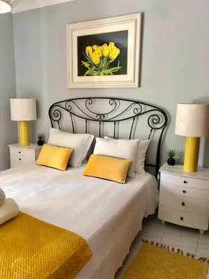 a bedroom with a bed with two lamps and yellow pillows at Amazing Ocean View Apt Steps from the Beach in Quarteira