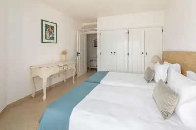 a white bedroom with a bed and a desk at Moradia Olhos de Água - 3 quartos - 6 camas in Albufeira