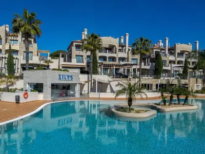 a street with palm trees and people walking down the street at Apartment Pine Hills Cristal by Interhome in Vilamoura
