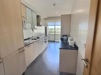 a kitchen with white cabinets and a black counter top at Marina Vilamoura - Aquamar 201 - By Vilamoura Sun in Quarteira