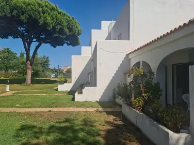 a white building with a tree in the background at Vilamoura Alecrim in Vilamoura