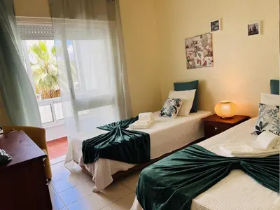 two beds in a room with a window at Julias Beach Retreat in Quarteira