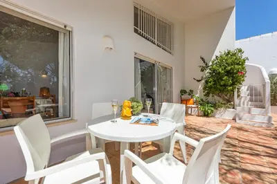 a white dining room with a white table and chairs at Villa Bolota in Albufeira
